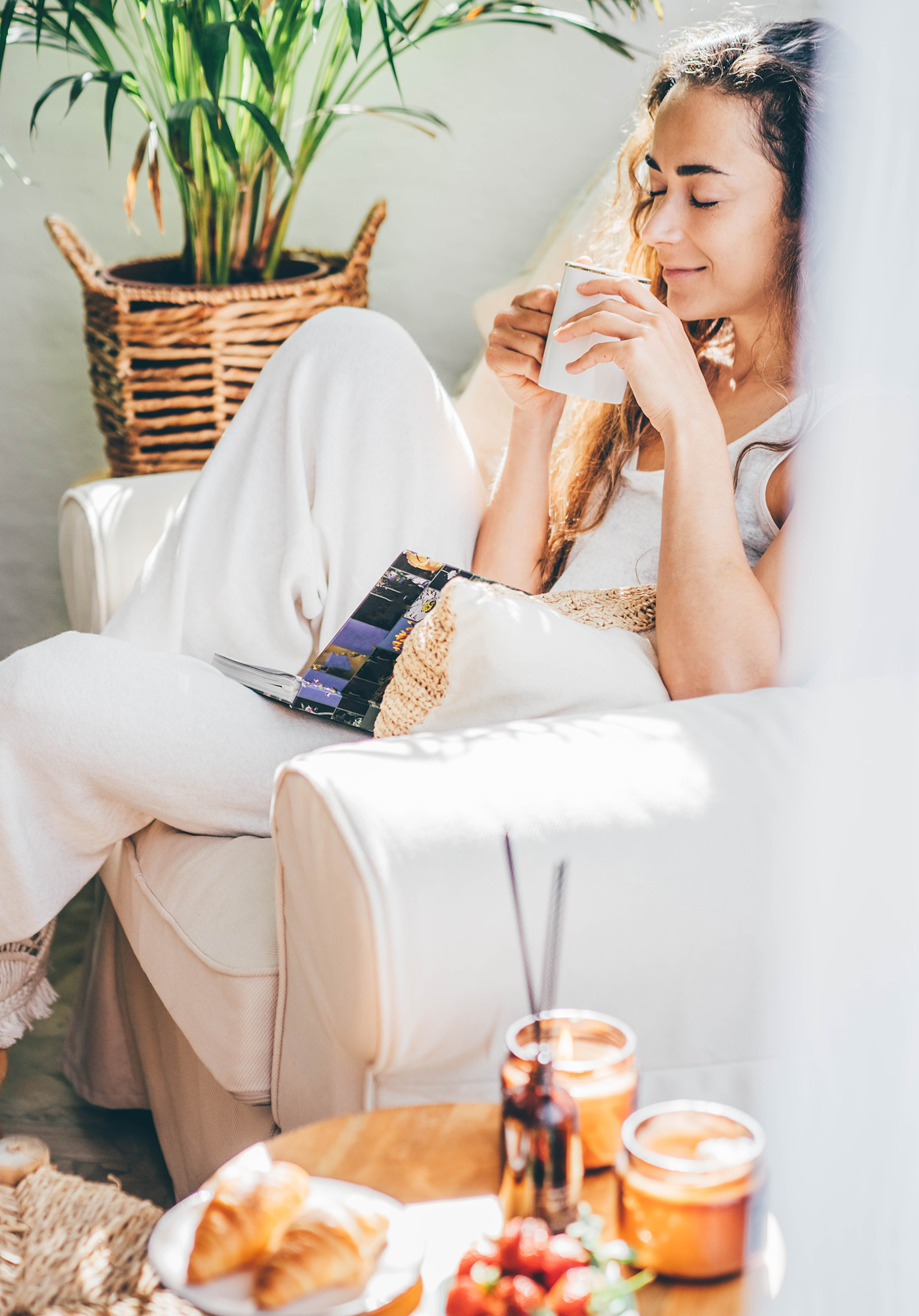 Lady relaxing on sofa drinking coffee with fruits and scones on buffet table of rental property